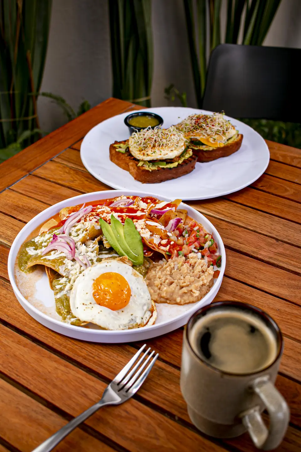 Mesa en la terraza con chilaquiles, avocado toast y café